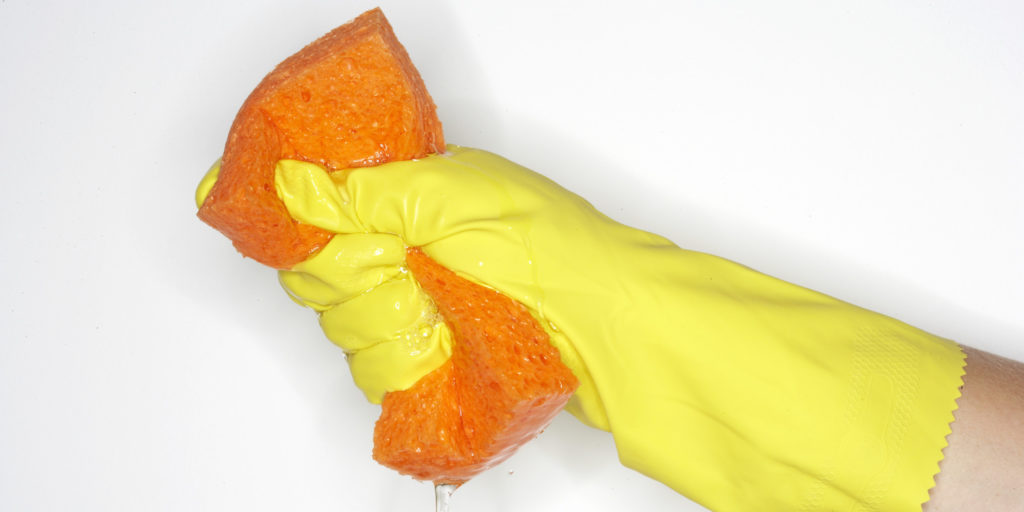 hand with rubber glove holding wet sponge